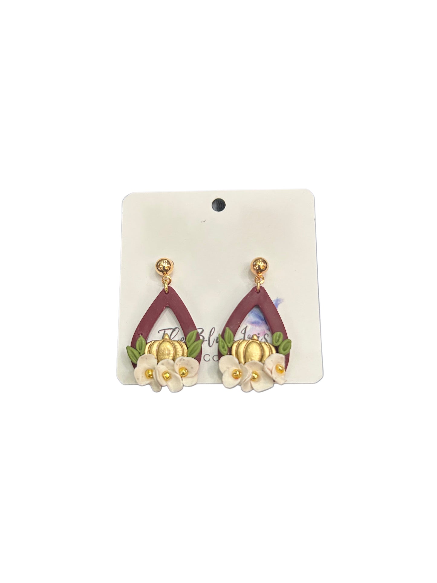 Handcrafted autumn earrings with pumpkin and floral design on burgundy clay teardrops.