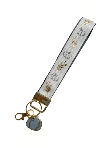 Autumn-inspired wristlet keychain featuring gold leaf ribbon and pumpkin design