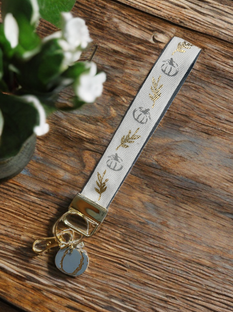 Handmade wristlet keychain with gold metallic leaf ribbon and polymer clay grey pumpkin charm