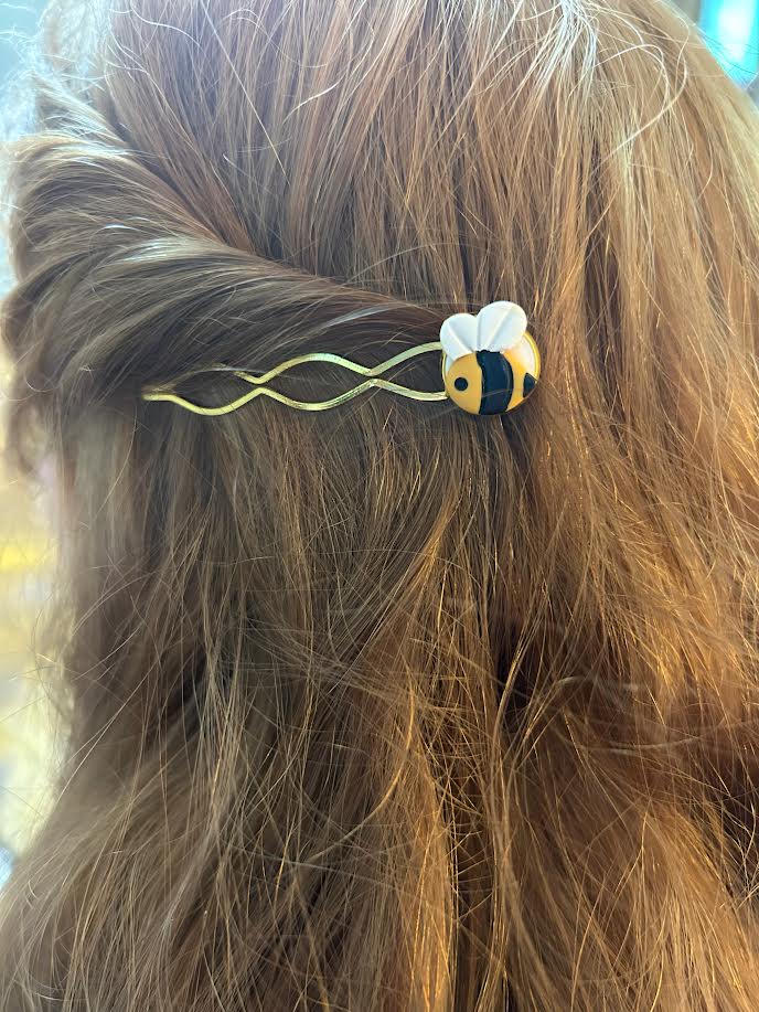 Handmade polymer clay bee hair pin with gold accent in a person's hair