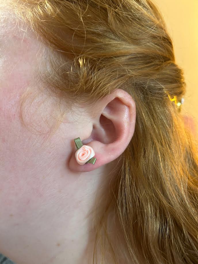 Close-up of fabric rose stud earring paired with elegant pearl design